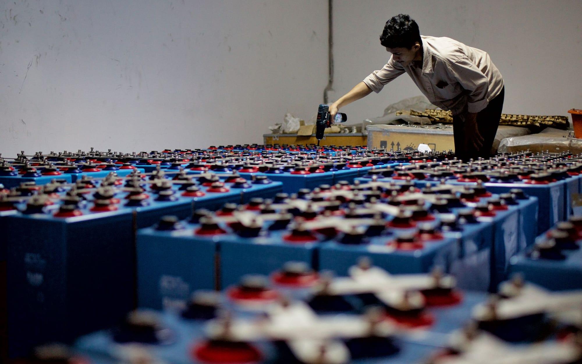 Technician inspecting rows of industrial battery cells