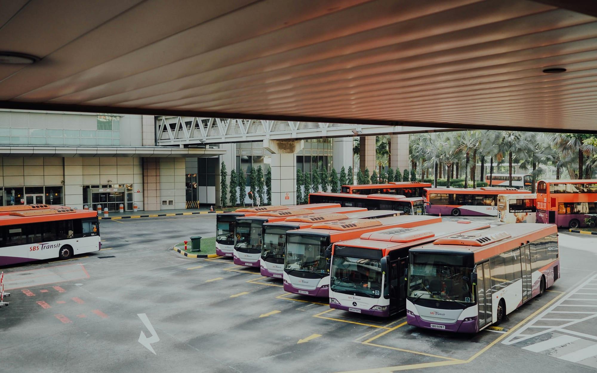 Row of buses parked at a depot under a canopy