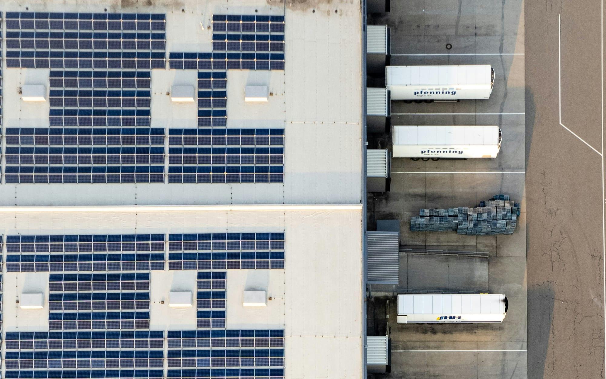 Aerial view of a factory roof covered in solar panels beside a loading dock